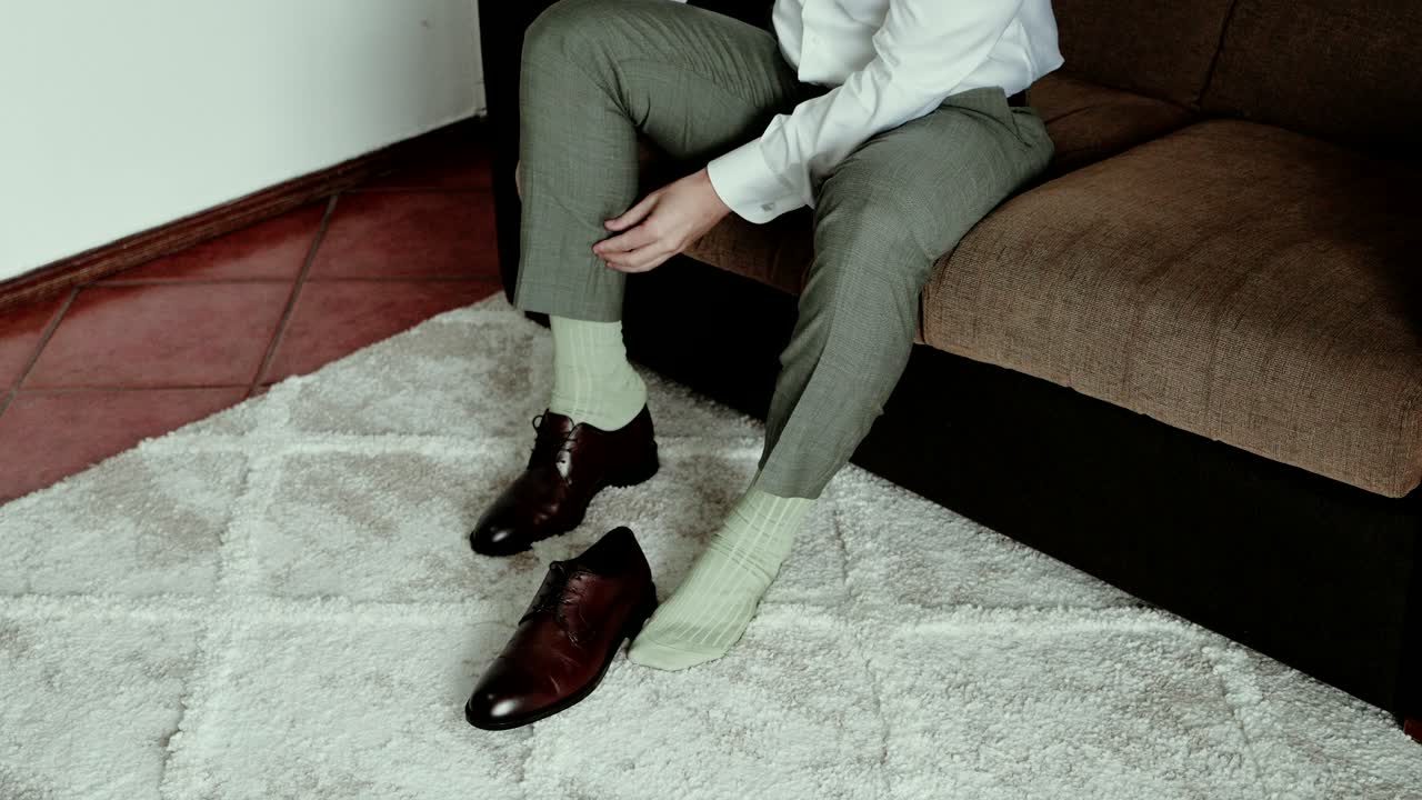 Uomo in abito formale che si prepara le scarpe in casa prima della cerimonia nuziale