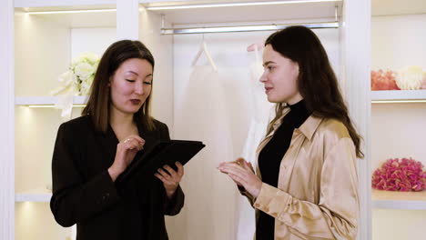 y mujer caucásica asiática en la tienda de vestidos de novia