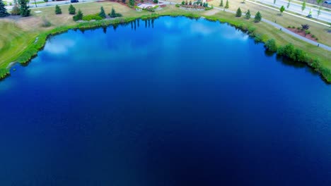 golf course aerial flyover reflective birds top eye view over garden waterfall tiered from pond to pond closeup shore pathway next to roadway in the southside of edmonton alberta canada