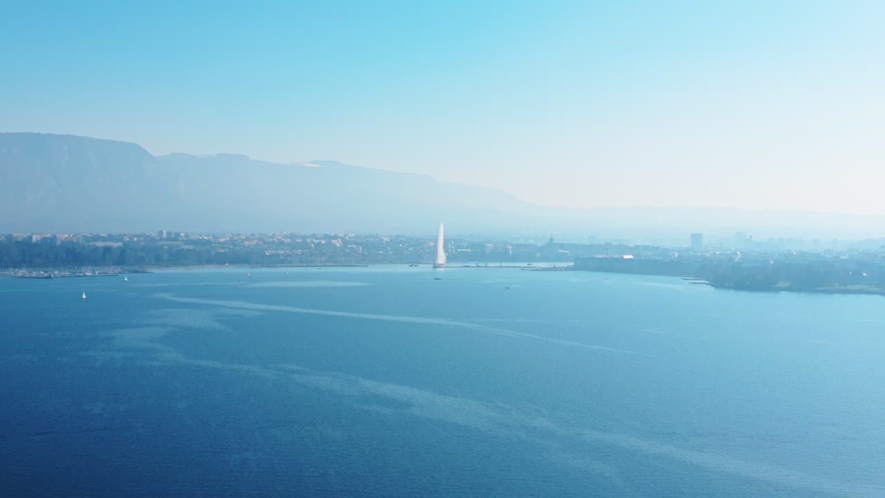 スイス、ジュネーブのジュネーブ湾を日中に空撮。噴水が写っており、ドローンによるドリーアウトショット。