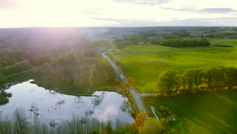 Luftaufnahmen-Am-Teich-Im-Herbst,-Bäume-Ohne-Blätter,-Kahle-Baumstämme,-Bunte-Landschaft-Ringsum,-Schöner-Sonnenuntergang,-Ermland-Und-Masuren,-Polen