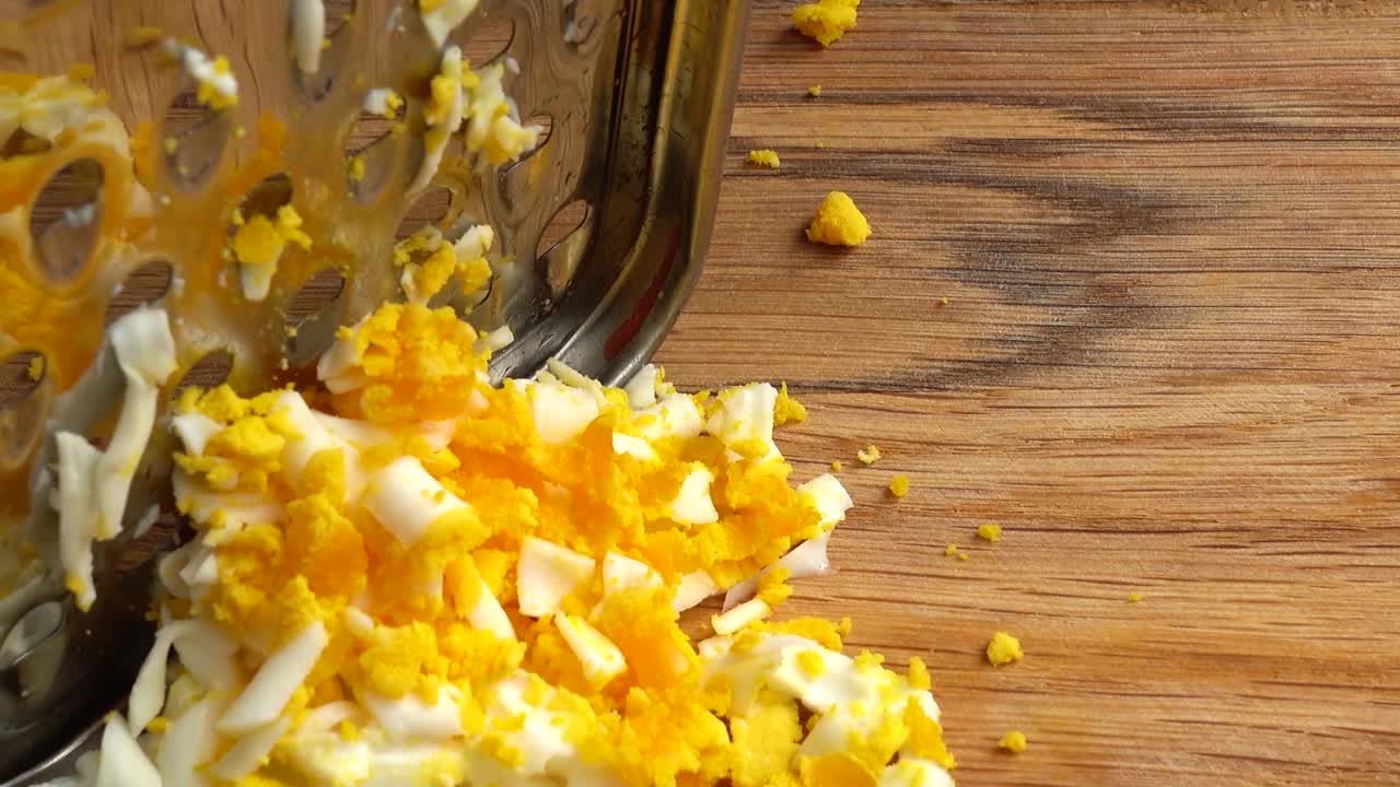 Il cuoco grattugia l'uovo. Lavoro del cuoco.