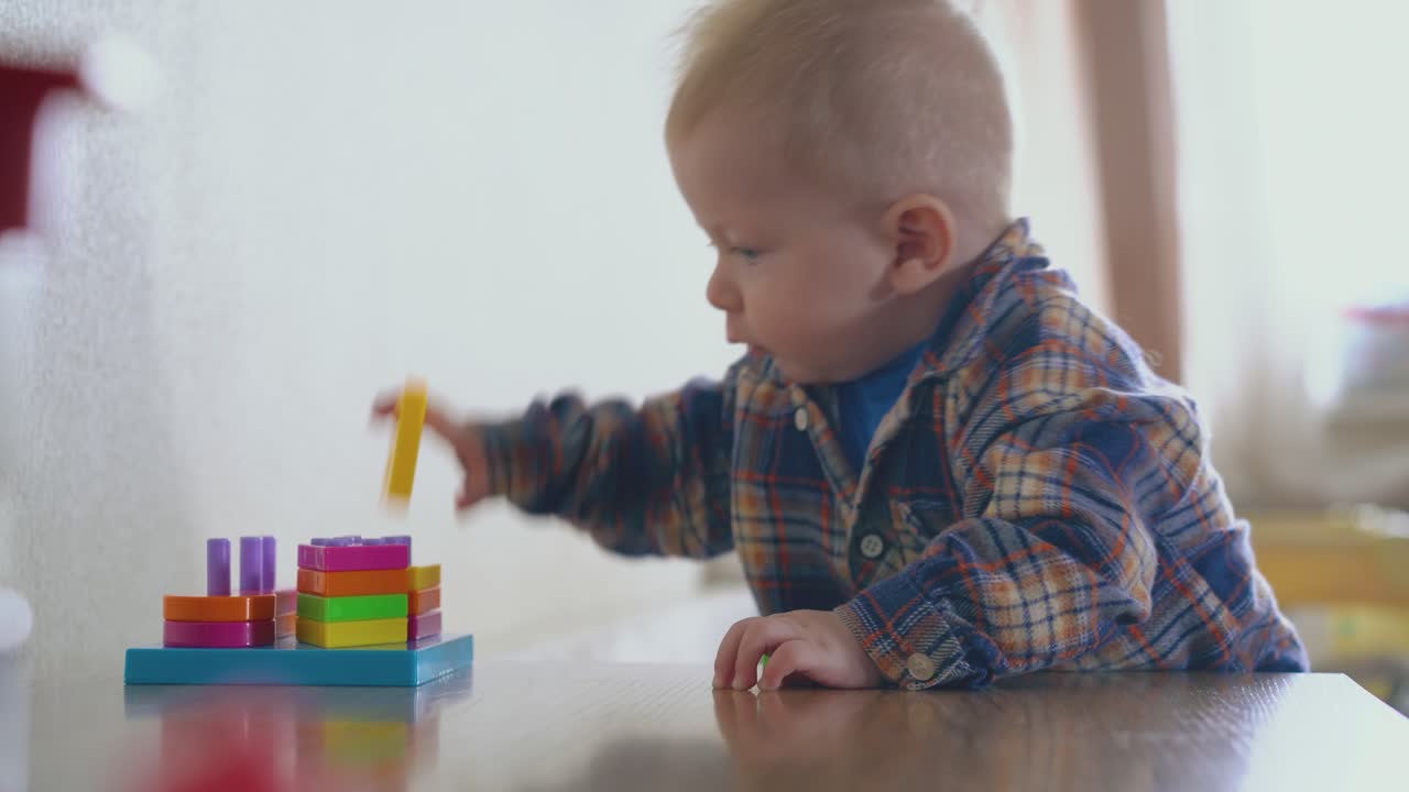 un bambino carino gioca con un giocattolo colorato in piedi a un tavolo di legno
