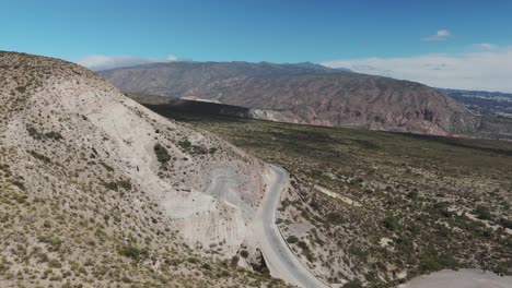 Aerial-above-car-driving-scenic-route-through-mountain-road-in-Amaicha-del-Valle,-Argentina