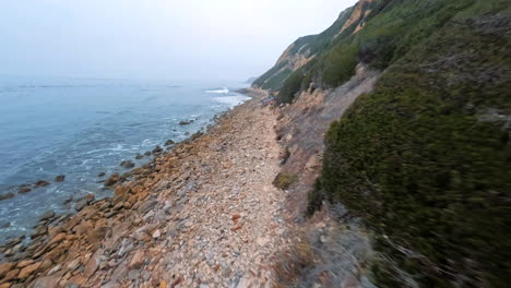 aerial fpv drone shot of the landscape in palos verdes near los angeles with a view of mountains, rocks and the rocky beach with the blue sea