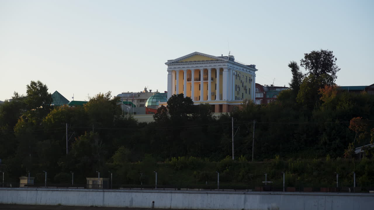 A classical building with columns behind a treeline