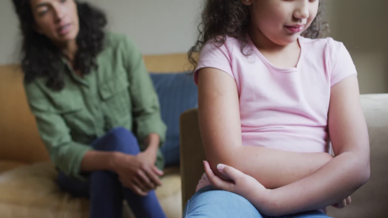Madre multietnica che consiglia la sua figlia triste sul divano in salotto