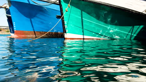 Reflection-in-harbour-water-of-hulls-of-colourful-boats