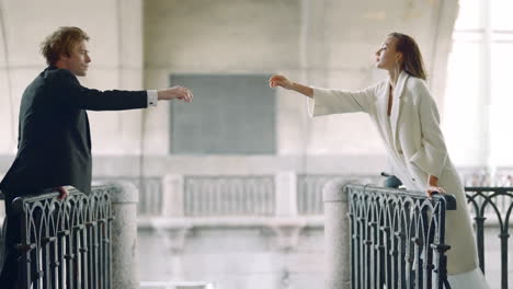 couple reaching out on a bridge