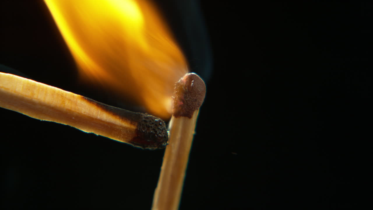 un fósforo encendiendo otro contra un negro