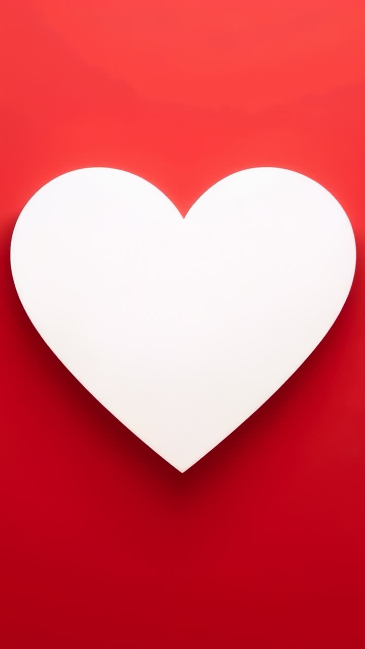 Video verticale: cuore bianco iniziale che cresce fino a riempire l'inquadratura con gradiente rosso e leggera ombra portata