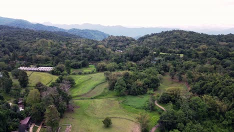 Luftdrohne,-Die-Sich-Tagsüber-über-Hütten-über-Einer-Wunderschönen-Bergkette-Im-Tham-Pha-Suea-Nationalpark-Rückwärts-Bewegt