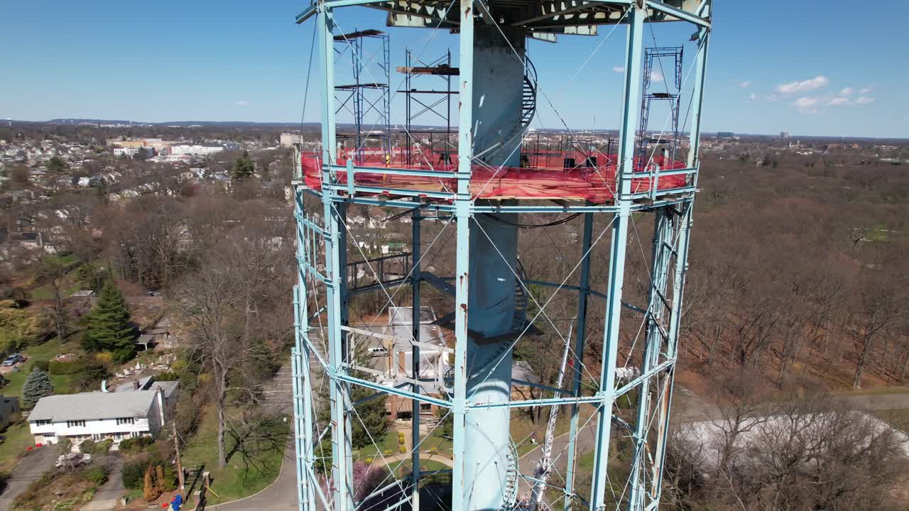 una vista aérea de una torre de agua siendo desmantelada en un día soleado en long island, nueva york