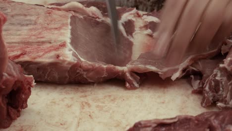 carnicero cortando carne en la mesa de la carnicería pública en el mercado
