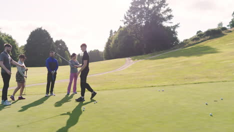 Group of golf players playing golf together, hitting the ball with club on a golf course