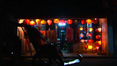 bicycles and rickshaws pass a colorful lantern store at night in vietnam