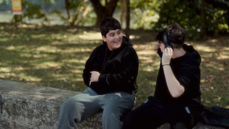young friends share headphones and chat in a park
