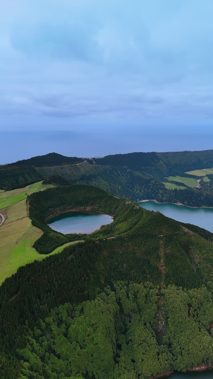 Approaching the mount covered with lush greenery. Mountains and valleys of the Azores, top view. Vertical video.