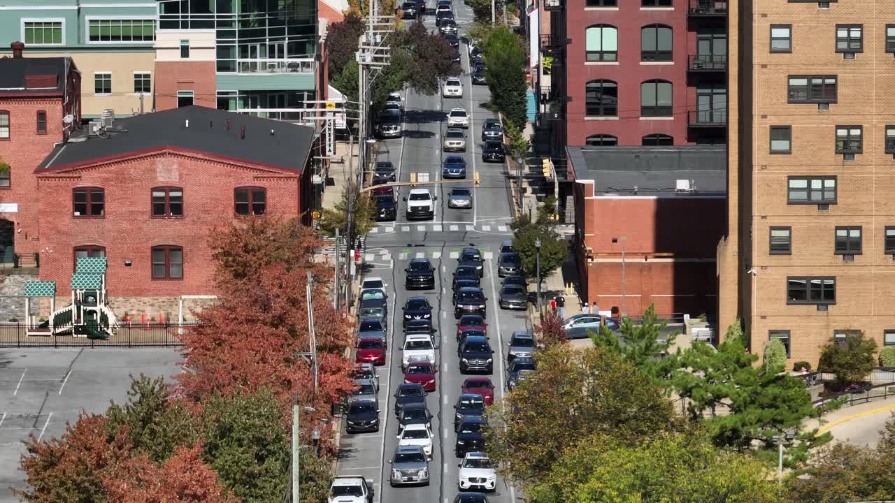 Busy traffic scene on hilly Main Street of Lancaster downtown. Sunny day between high-rise apartment blocks in autumn. Drone wide shot. Pennsylvania, USA