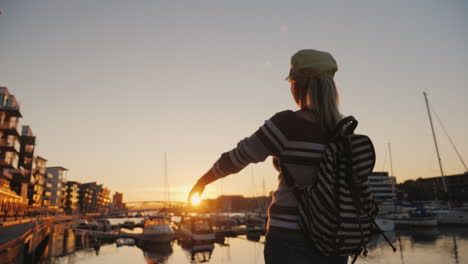 mujer activa se regocija al amanecer sobre el puerto deportivo corre hacia adelante levanta las manos al amanecer en bergen