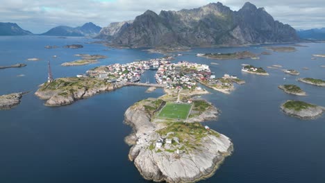 henningsvaer soccer field and village in lofoten island archipelago, norway - 4k aerial tilting down