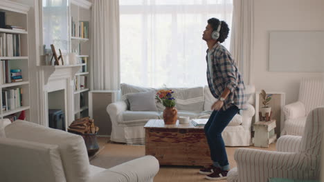 Un-Joven-Feliz-Bailando-En-Casa-Celebrando-El-éxito-Escuchando-Música-Usando-Audífonos-Divirtiéndose-Bailando-En-La-Sala-De-Estar-El-Fin-De-Semana