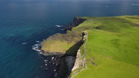 tourists walking along cliffs of moher walking trail, ireland, aerial flyover