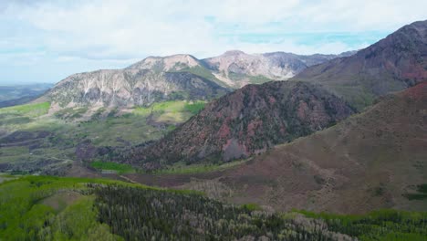 hd aerial drone view of beautiful countryside mountains during cloudy summer day and vibrant green pine tree and aspen tree forest valleys at the base near telluride colorado usa