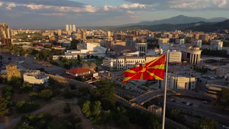 video aéreo de la ciudad de skopje en el norte de macedonia con la bandera del norte de macedonia ondeando en el viento