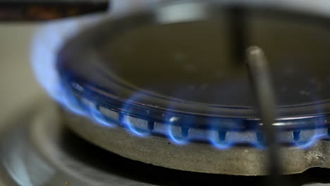 Close-up-of-stove-gas-burner-with-burning-blue-flame