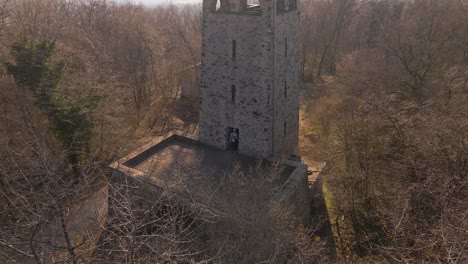 static aerial shot through a bare tree of a young man exploring the first level of the wetzlar tower