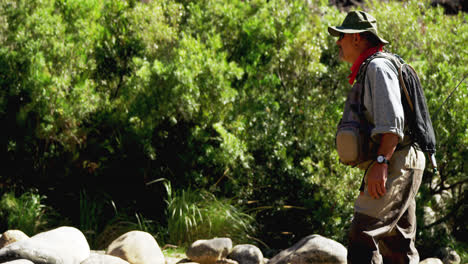 Fly-fisherman-standing-on-rock-near-riverside