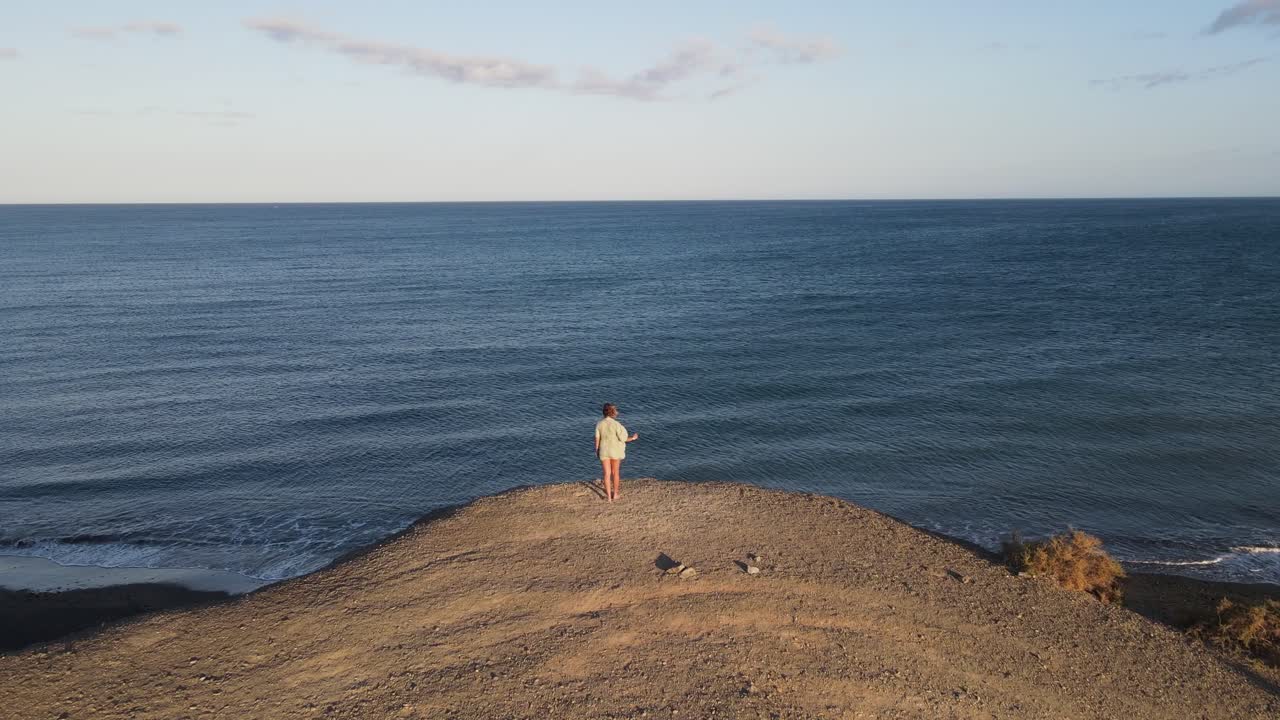 바다, 카나리아 제도, 푸에르테벤투라 앞 절벽에 서 있는 여성의 공중 드론 샷