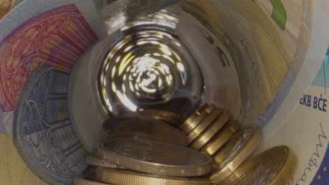 dolly shot showing tunnel of rotated euro banknotes and several coins