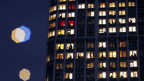city skyscraper at night with people in windows