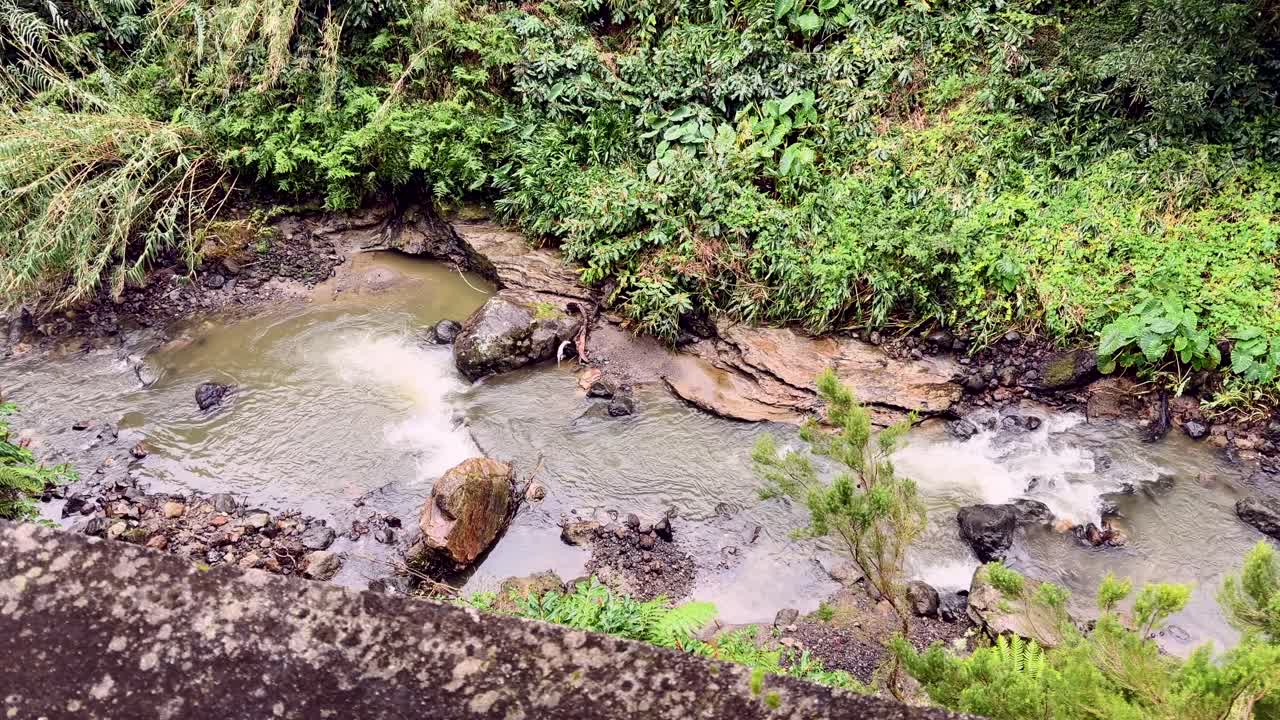 Sungai kecil mengalir di antara bebatuan dan vegetasi Sao Miguel Azores