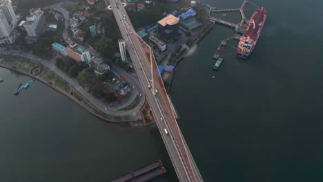 suspension bridge above shipping lane - orbiting aerial drone shot