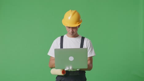 Asian Man Painter Wearing Safety Helmet Using A Laptop While Standing In The Green Screen Background Studio