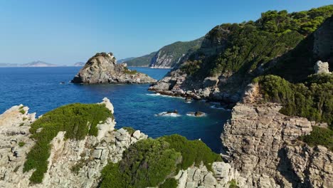 a rocky coastline with clear blue waters and lush green vegetation, aerial view