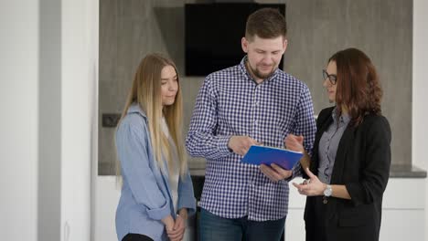 real estate agent with papers giving key to man and woman while moving in to apartment