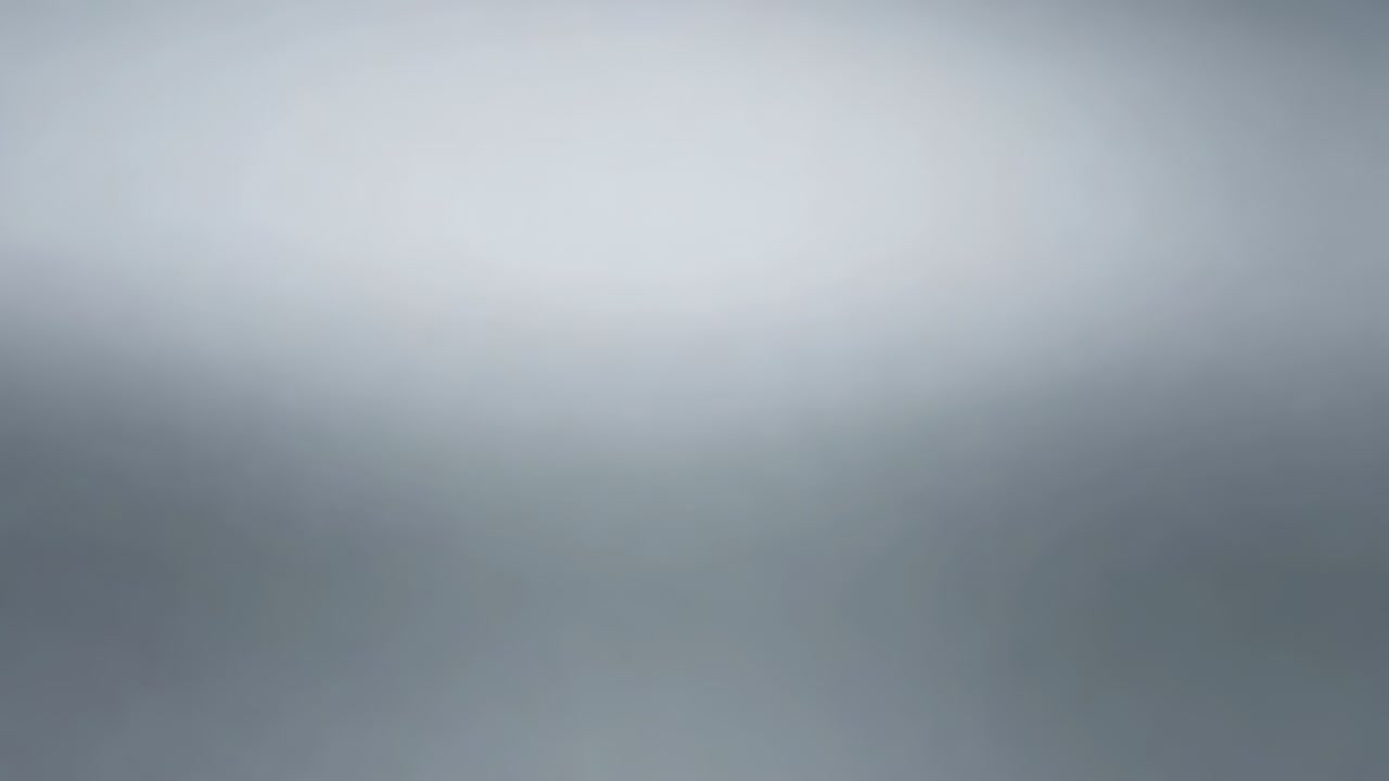 Playback starting camera capturing soft gray gradient shifting blur on gray field, brief dark spot
