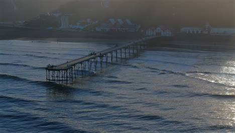 establishing drone shot of saltburn-by-the-sea pier at high tide uk