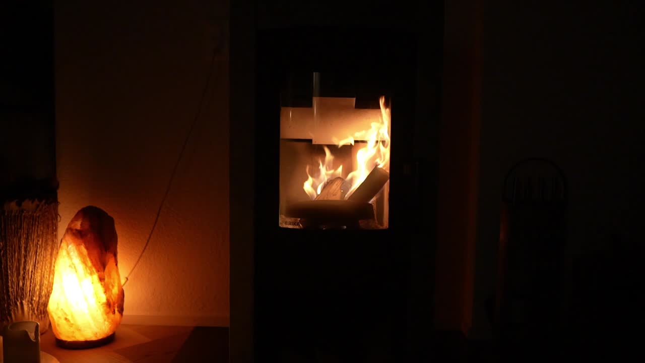A cozy fireplace burning wood with a warm salt lamp glowing in the background in Zürich