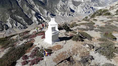 turistas parados cerca de dos pequeñas estupas con banderas de oración en la cima de una montaña en la caminata del circuito de annapurna, nepal