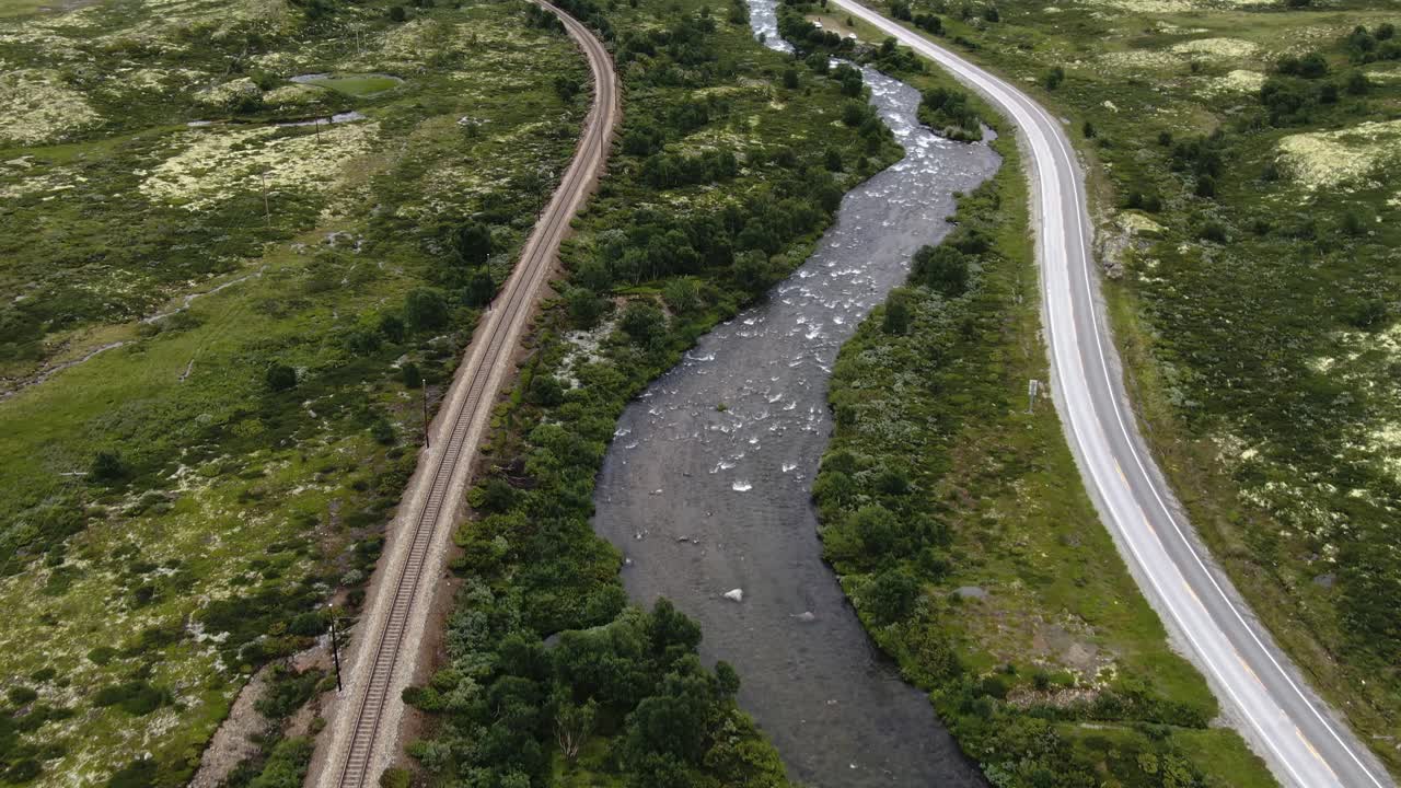 Droneopptak av togskinner ved en elv på et fjell.