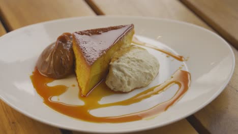 Close-up-shot-of-tasty-Creme-Caramel-with-ice-cream-served-on-white-plate