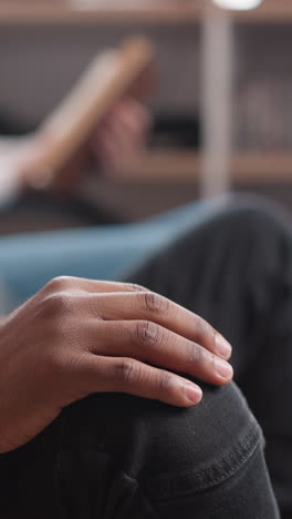 black man taps fingers on knee indoors closeup. african american guy listens to rhythmical music with friends in chill out corner. rest and relaxation