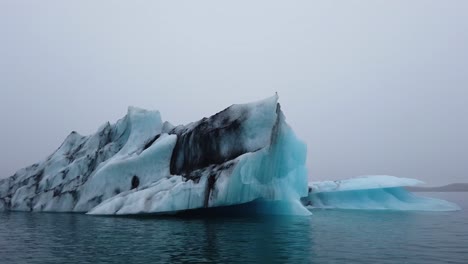 approaching big black and blue iceberg in jokusarlon glacier lagoon in south coast of iceland