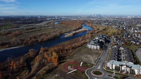 Aerial-shot-of-Bow-river-with-orange-fall-trees-and-Calgary-Downtown-in-background