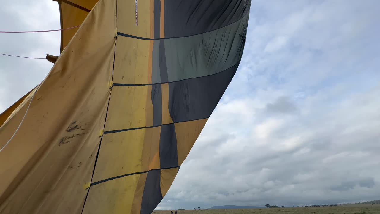 desinflación de globo de aire caliente y caída después del descenso en el parque nacional serengeti en tanzania.